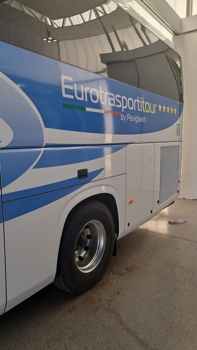 Autobus Eurolines blu e bianco parcheggiato al coperto, vista laterale vicino a una piattaforma del terminal.