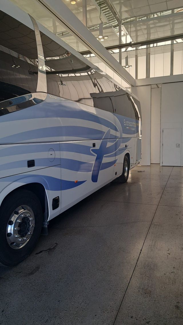 Autobus turistico bianco e blu parcheggiato all'interno di un garage o di un'officina.