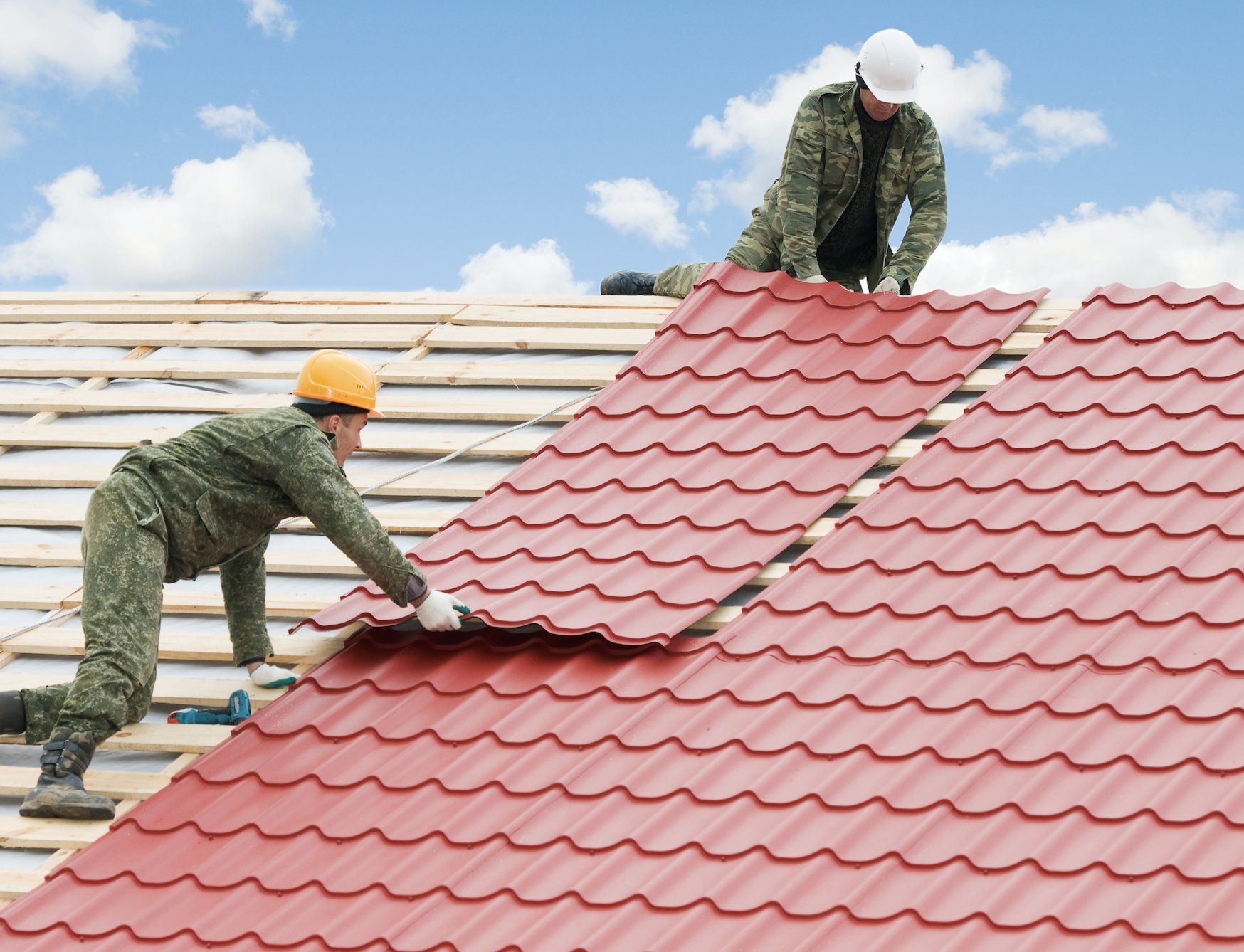 Roofing contractors installing metal roof panels
