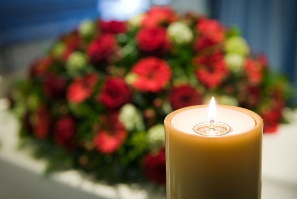 Una candela è accesa davanti a un mazzo di fiori.