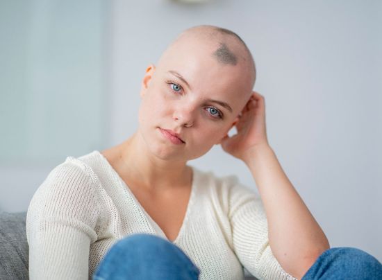 Una donna calva con un tatuaggio sulla testa è seduta su un divano.