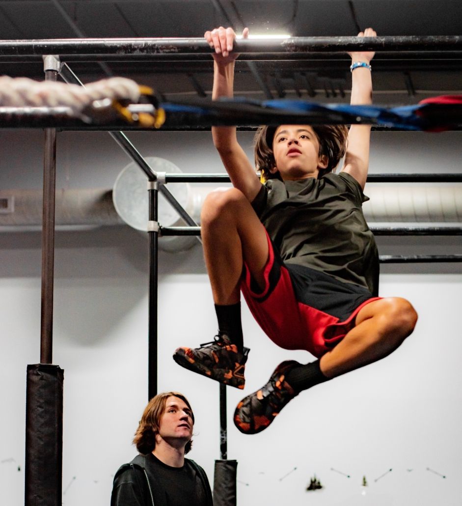 A female gymnast is standing on a balance beam.