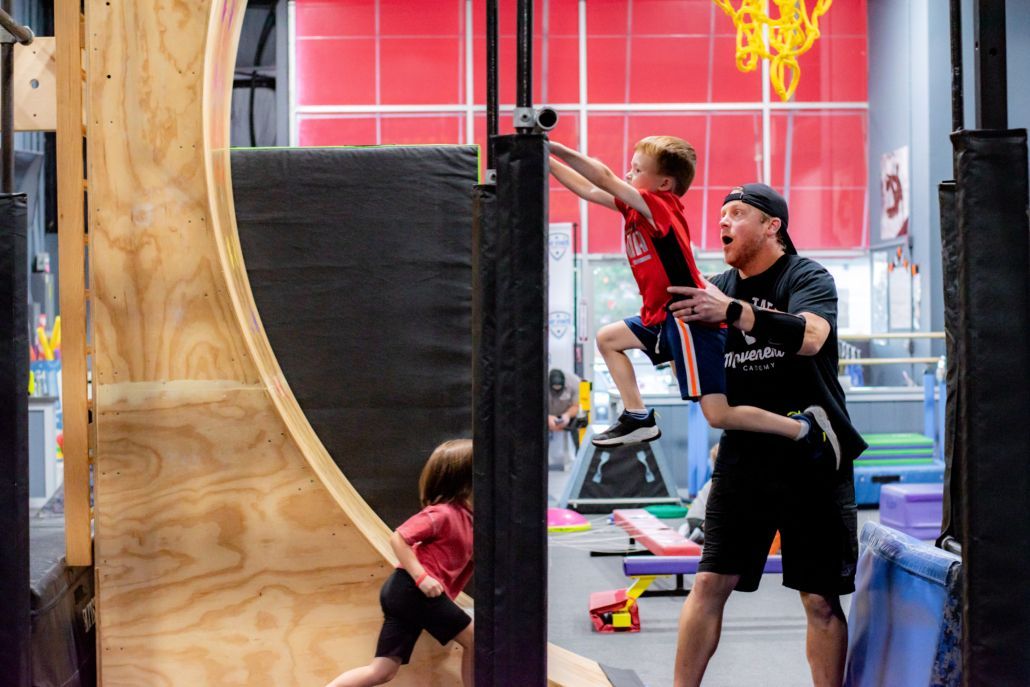 A young girl is sitting on a balance beam in a gym.