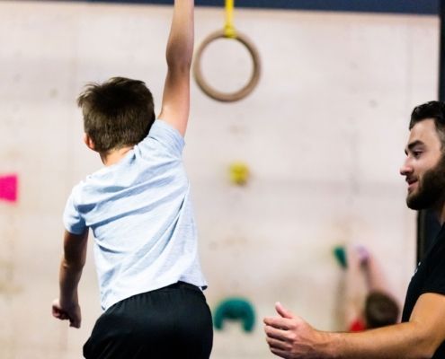 A young girl is sitting on a balance beam in a gym.