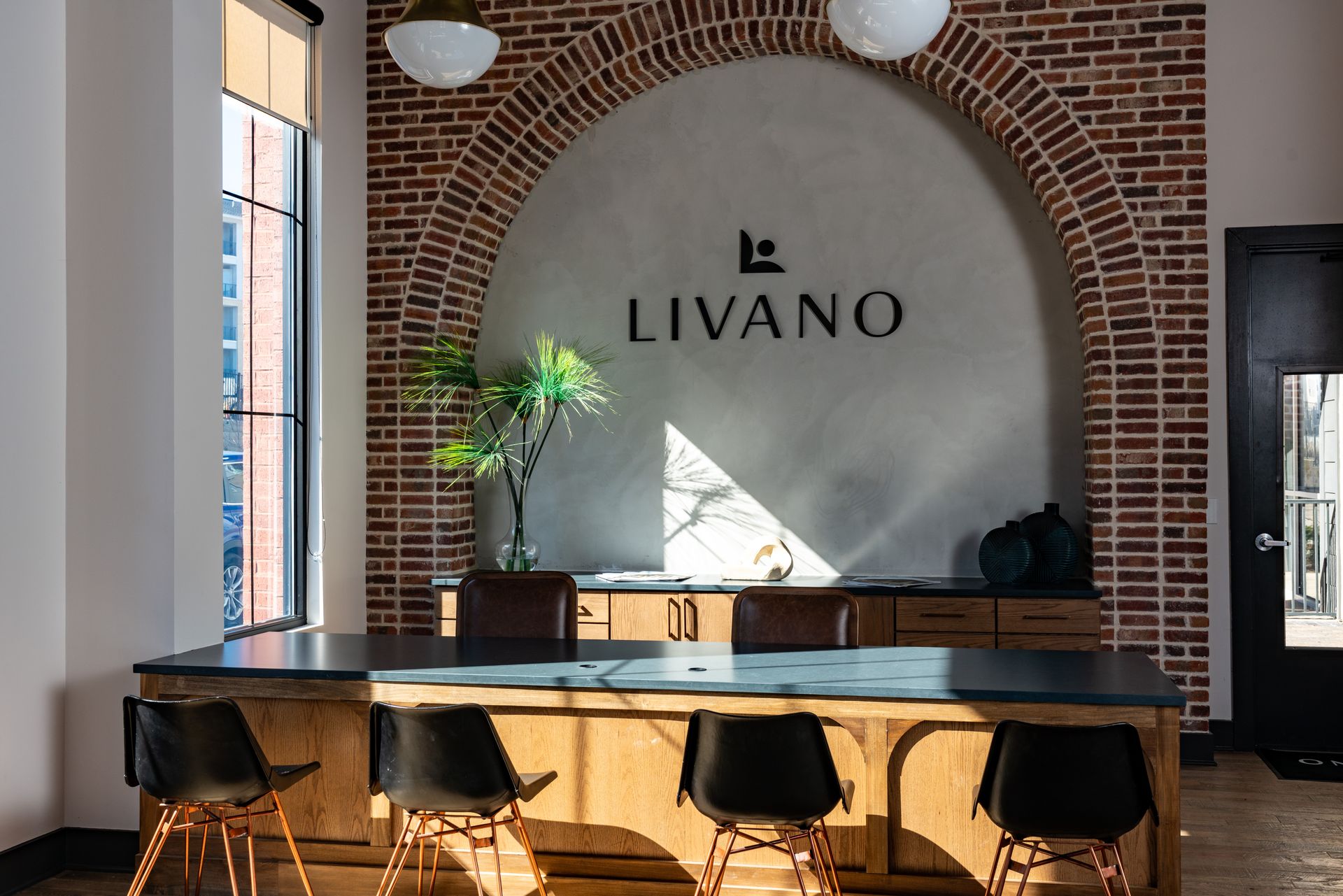 A room with a table and chairs and a brick wall with the word livano on it.