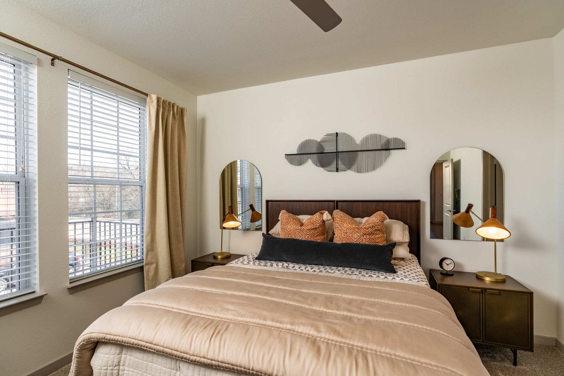 A bedroom with a bed , two nightstands , two windows and a ceiling fan.