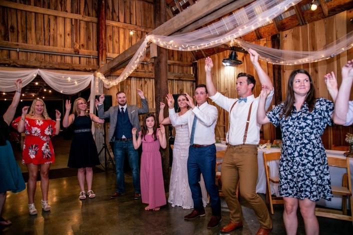 People dancing at a rustic indoor celebration with draped fabric and warm lighting