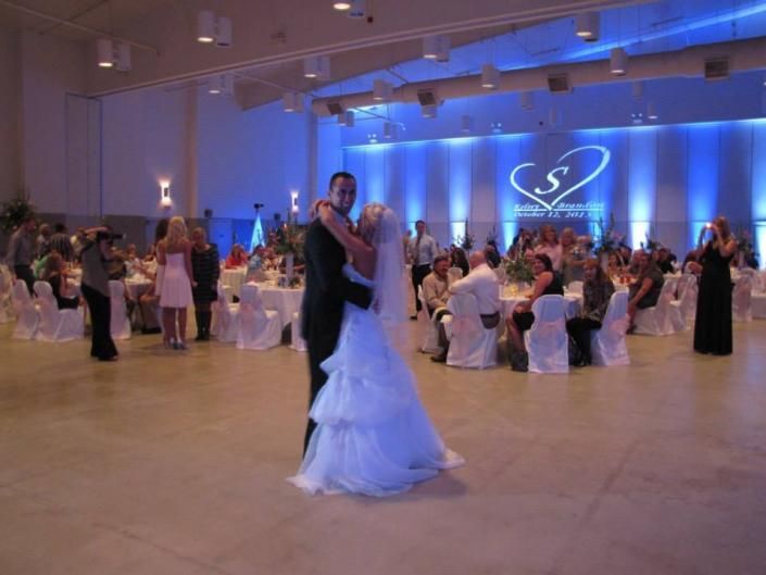 Couple dancing at a formal banquet in a blue-lit ballroom with seated guests nearby