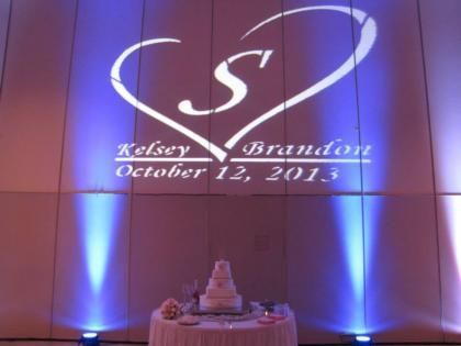 Projected heart monogram and “Kelsey & Brandon, October 12, 2013” on a wedding reception wall.