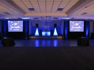Empty event stage with blue lighting and two projection screens in a conference hall