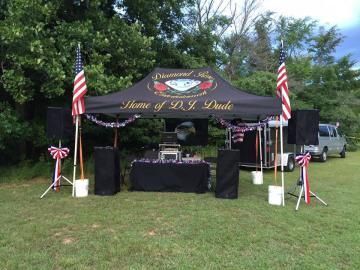 Black memorial tent with American flags and floral stands in a grassy outdoor setting