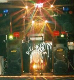 DJ booth with speakers, colorful stage lights, and a black draped table at a club or event venue