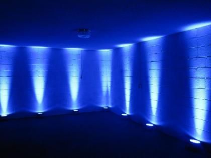 Blue-lit empty room with curved white walls and vertical light beams along the sides