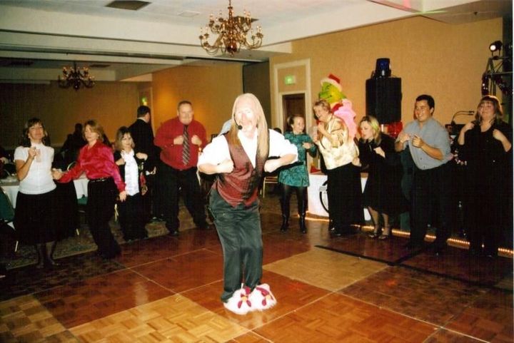 People dancing in a banquet hall, with a woman in white centered on the dance floor.