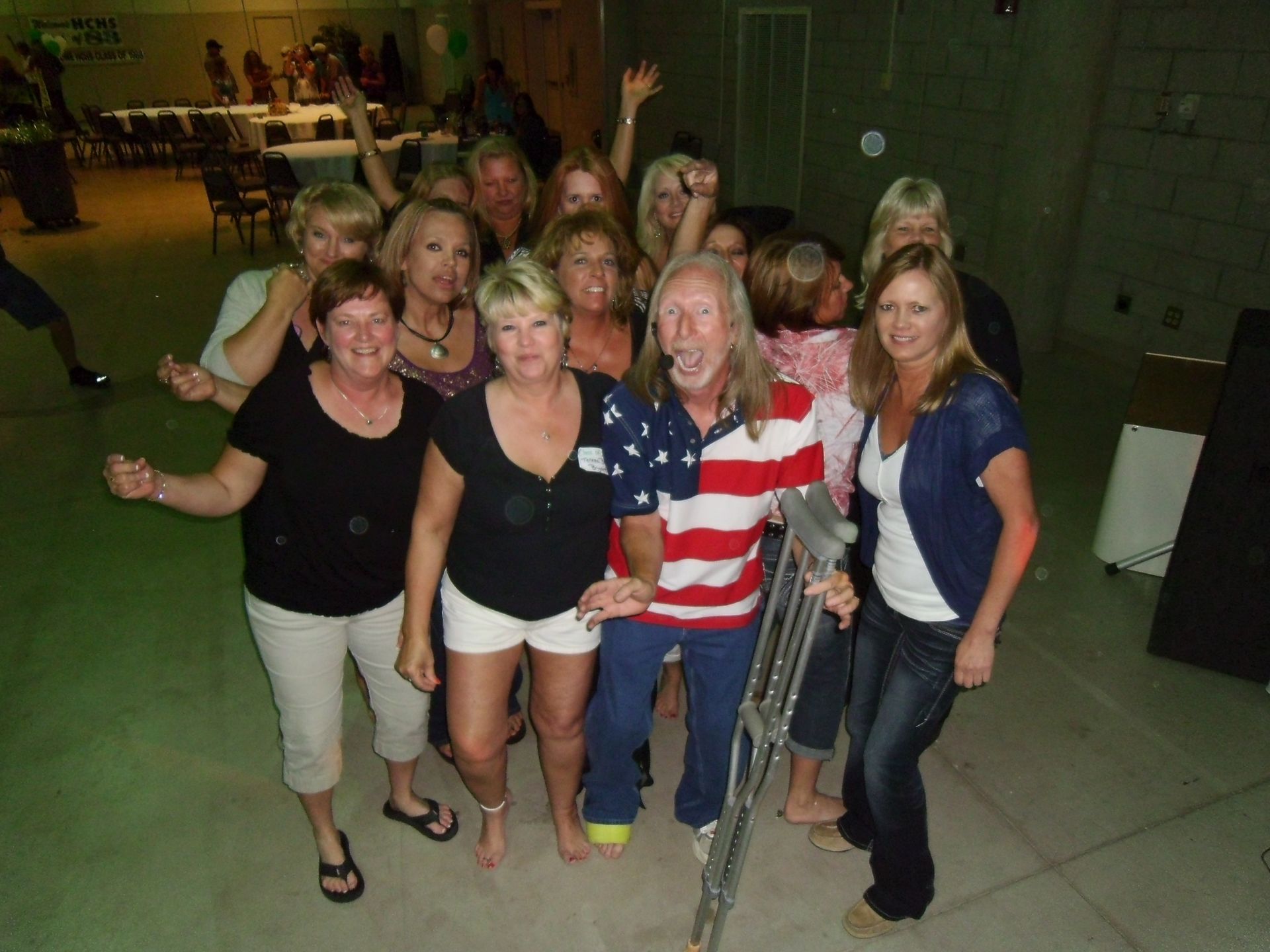 Group of women posing together indoors, one in an American flag shirt, smiling at the camera.