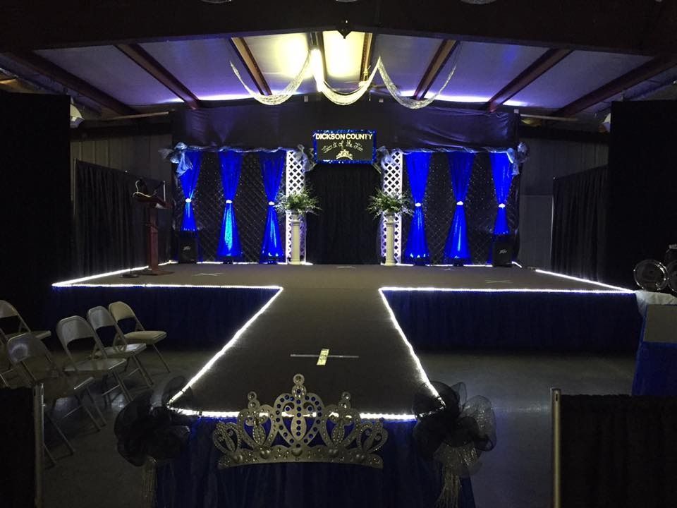 Elegant stage with blue uplighting, white-trimmed runway, and ornate black-and-gold decor