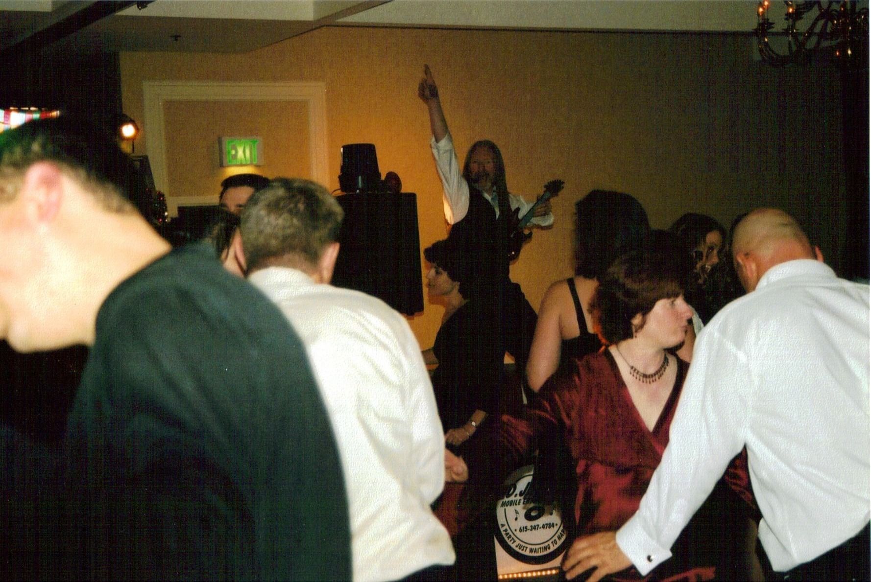 People dancing in a dimly lit indoor party, one person raising an arm in the center.