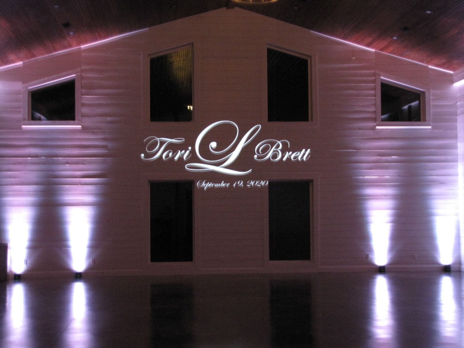 Pink-lit exterior of Tom's Bread building at night with glowing sign and tall windows