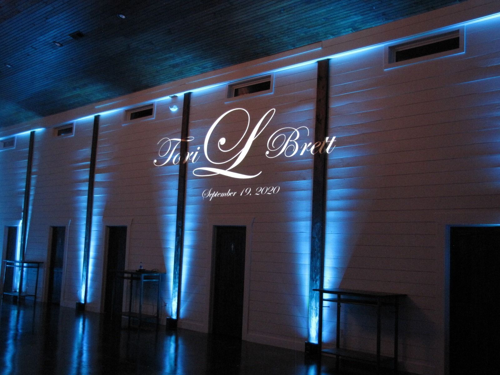 Nighttime exterior of a building with blue uplighting and a glowing script sign on the wall.