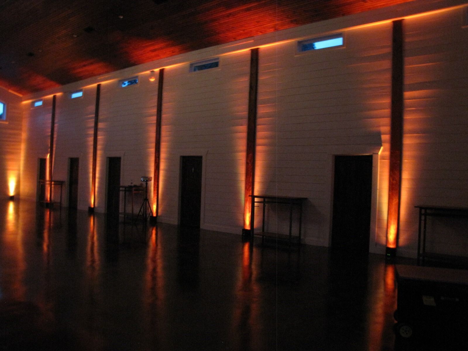 Dimly lit empty hall with vertical orange light columns reflecting on a glossy floor