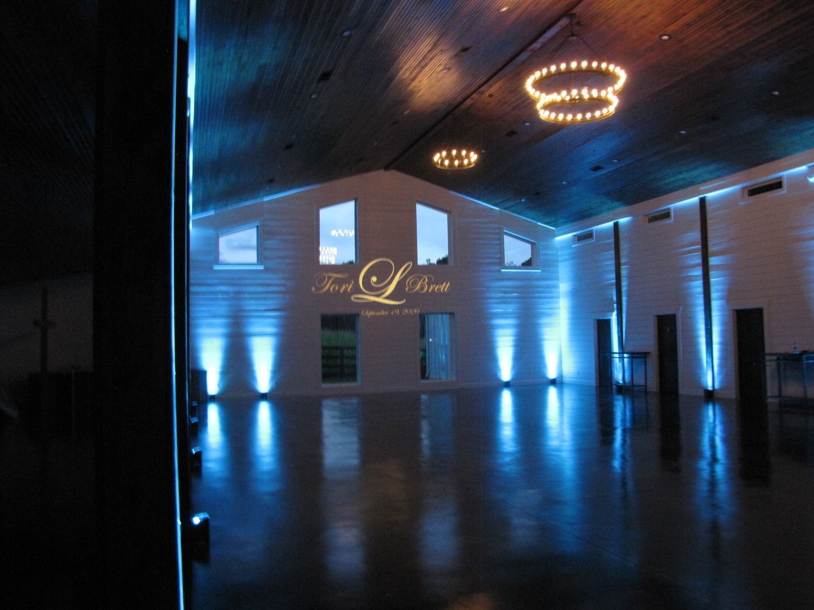 Empty modern event hall with blue uplighting and circular ceiling lights reflected on a dark floor