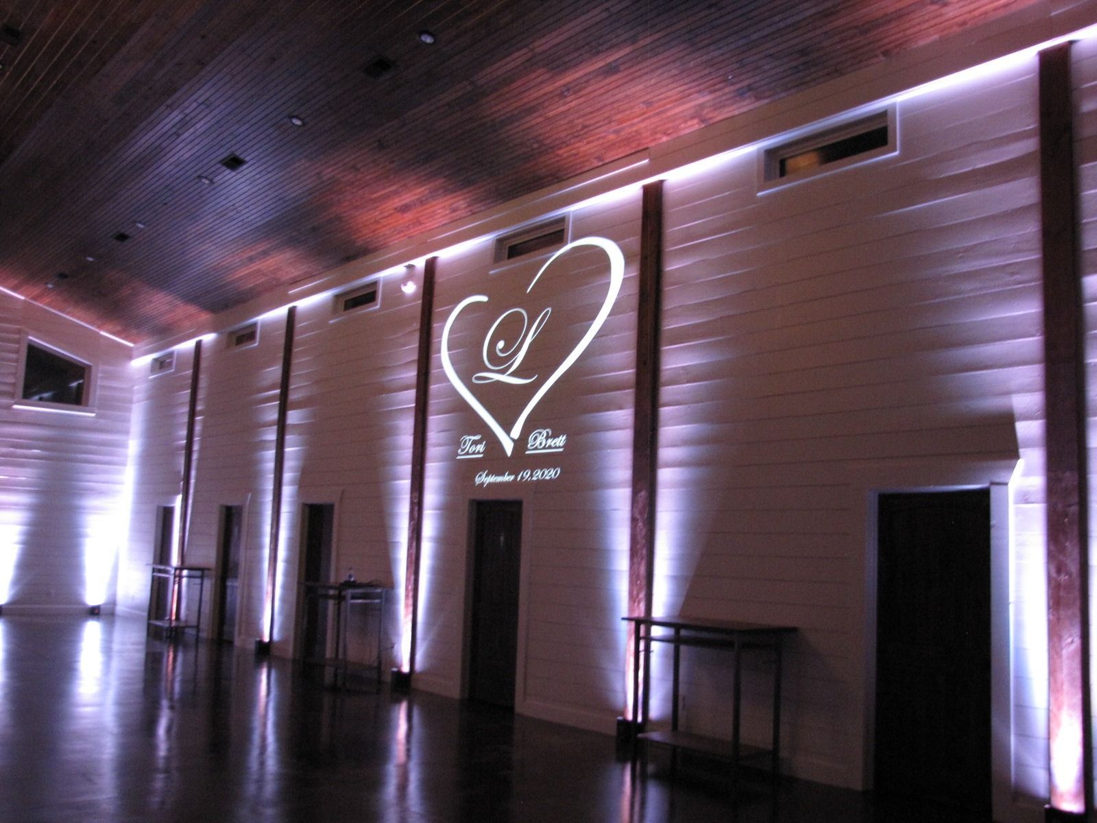 Dimly lit hallway with pink uplighting and a heart-shaped logo projected on the wall.