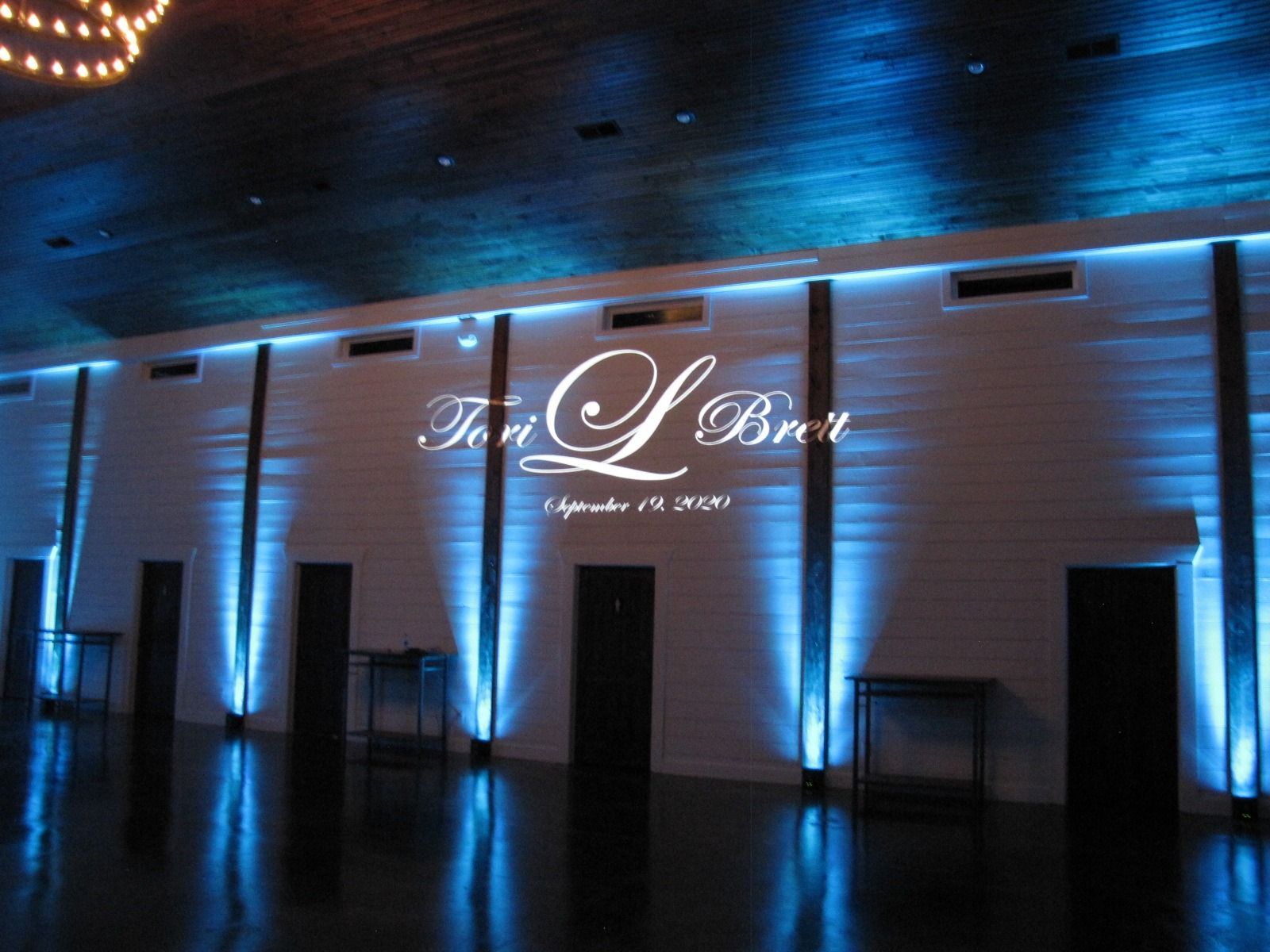 Elegant event hall exterior at night with blue uplighting and a lit sign above the doors