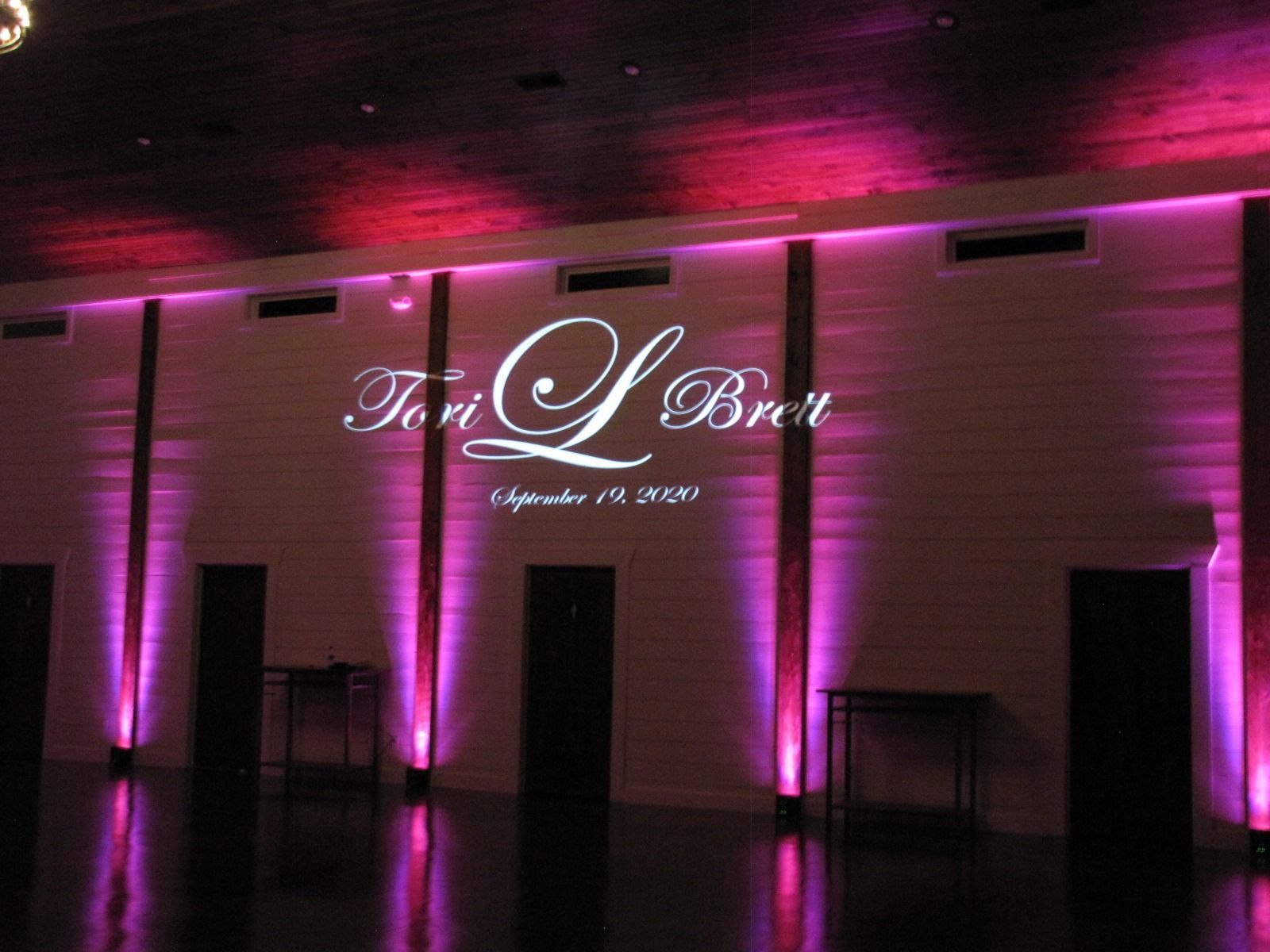 Purple-lit event wall with “Tori L. Brown” projected above three dark doors