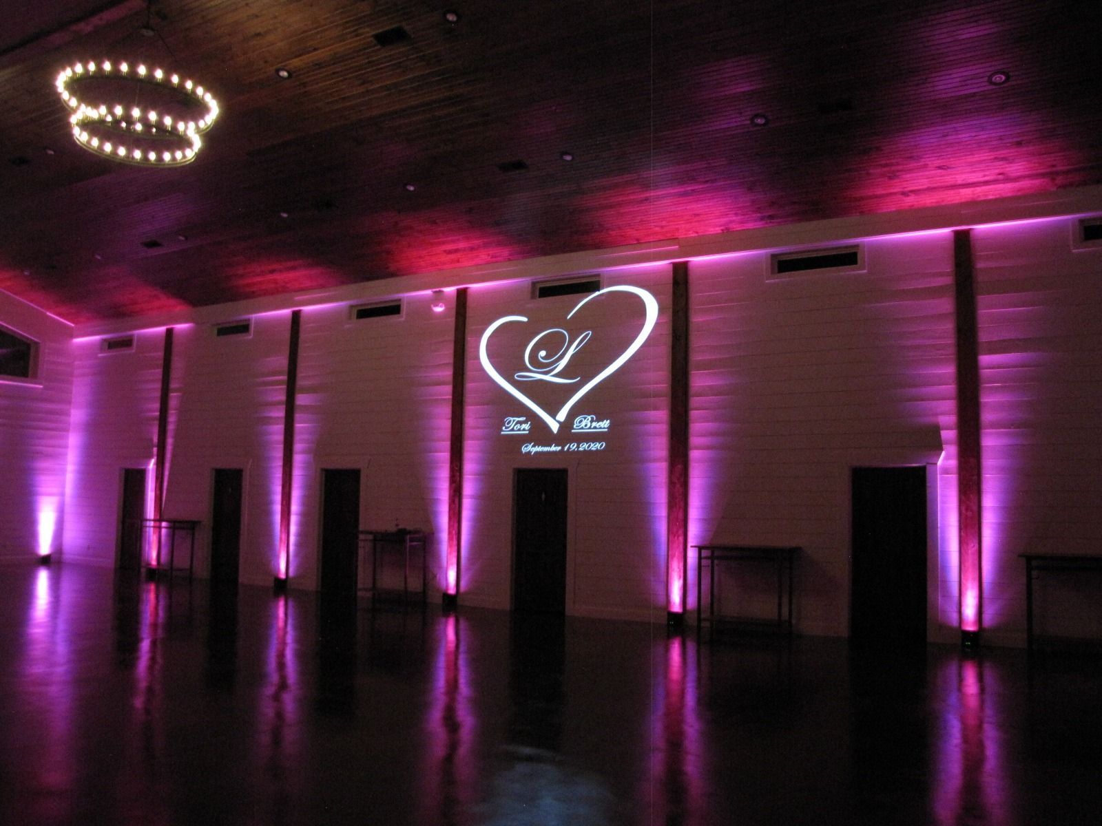 Pink-lit event hall with a heart logo projected on the wall and reflective floor