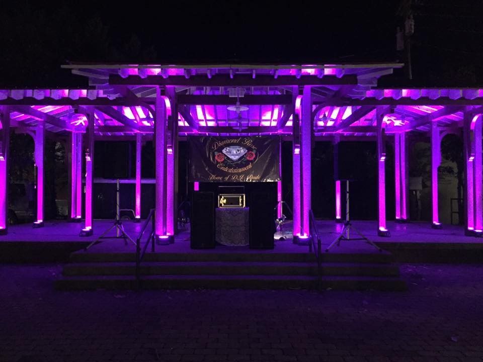 Nighttime building facade lit in vivid purple with columns and a central sign