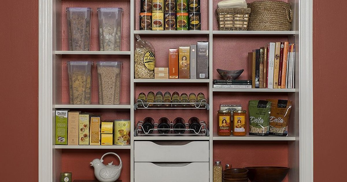 White pantry shelves filled with organized food items against a red wall.