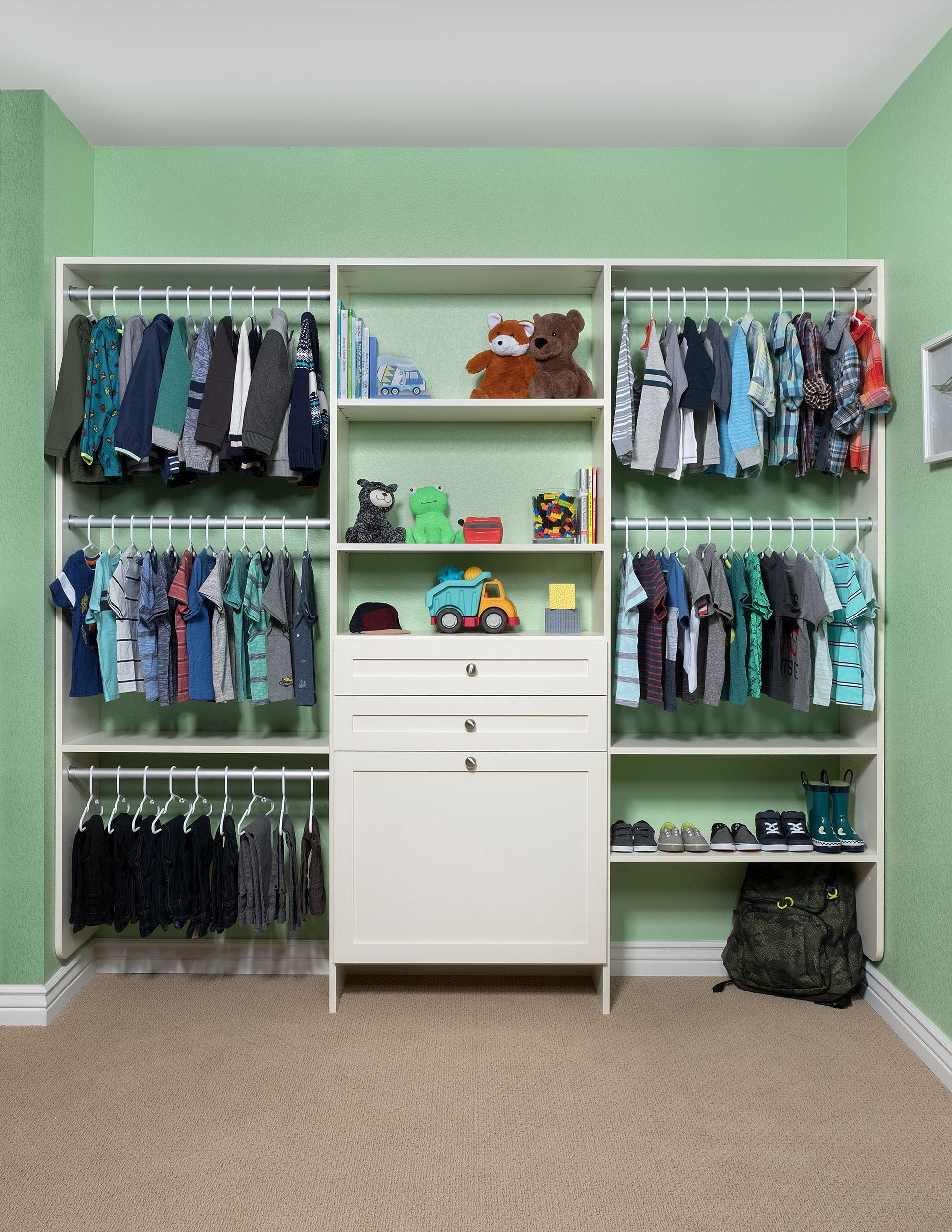 A well-organized walk-in closet with white cabinets, hanging clothes, drawers, shoe storage, and a center island.