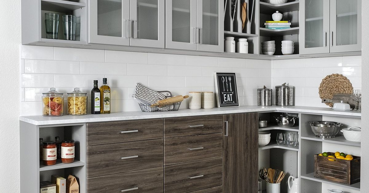 Kitchen with white and brown cabinets, white backsplash, and various kitchen items on countertops and shelves.