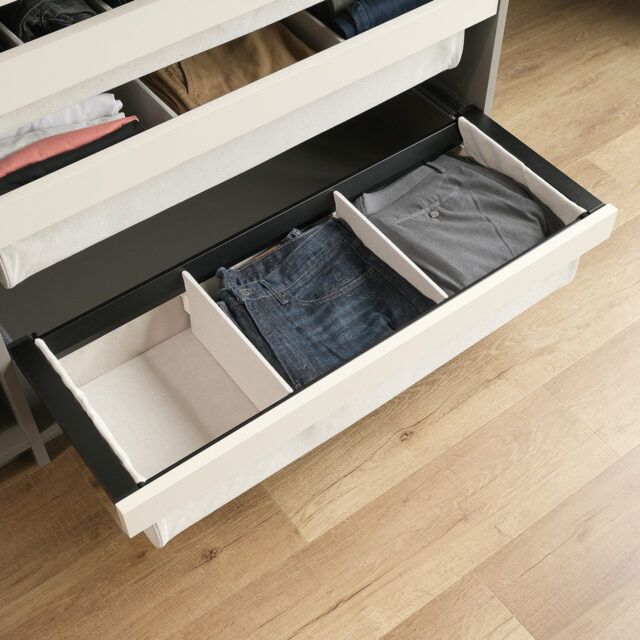 Closet with pull-out shelf holding folded dark blue sweater. Below are shelves with more folded clothes.