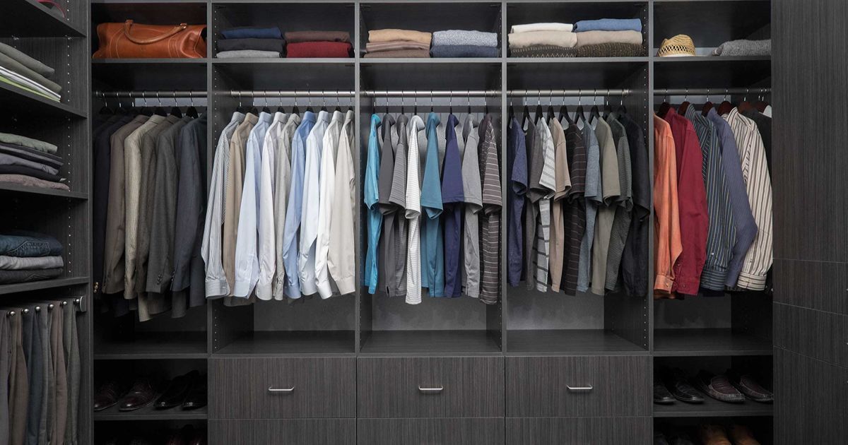 Dark closet with hanging clothes and shelves holding folded items.