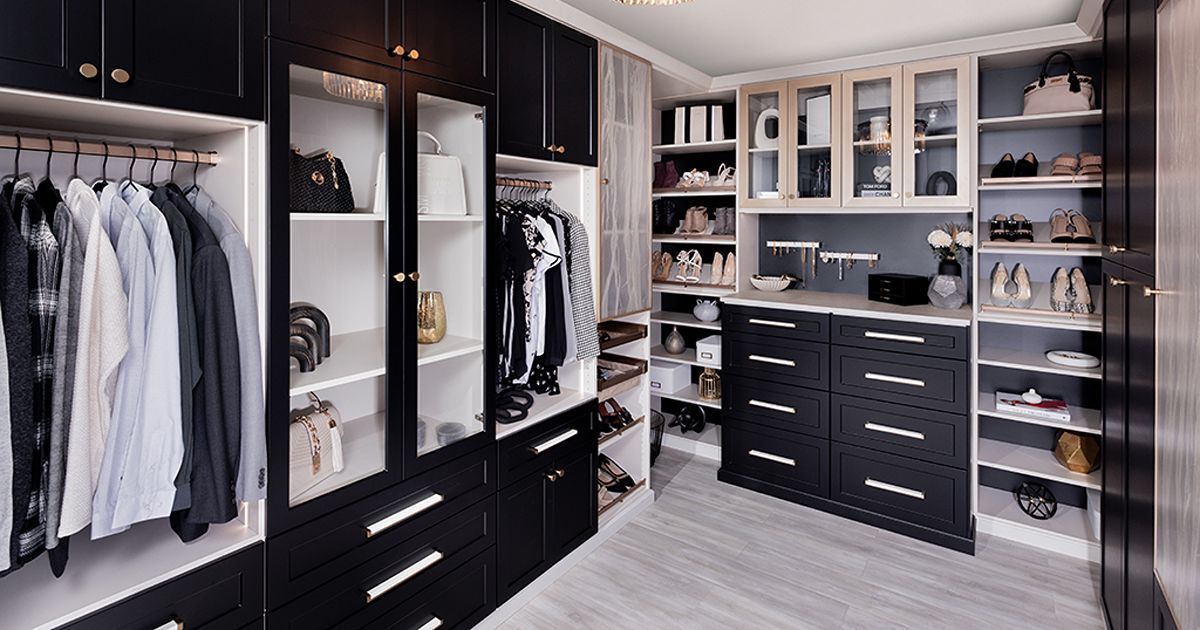 Walk-in closet with black and white cabinetry, clothes, and shoes.
