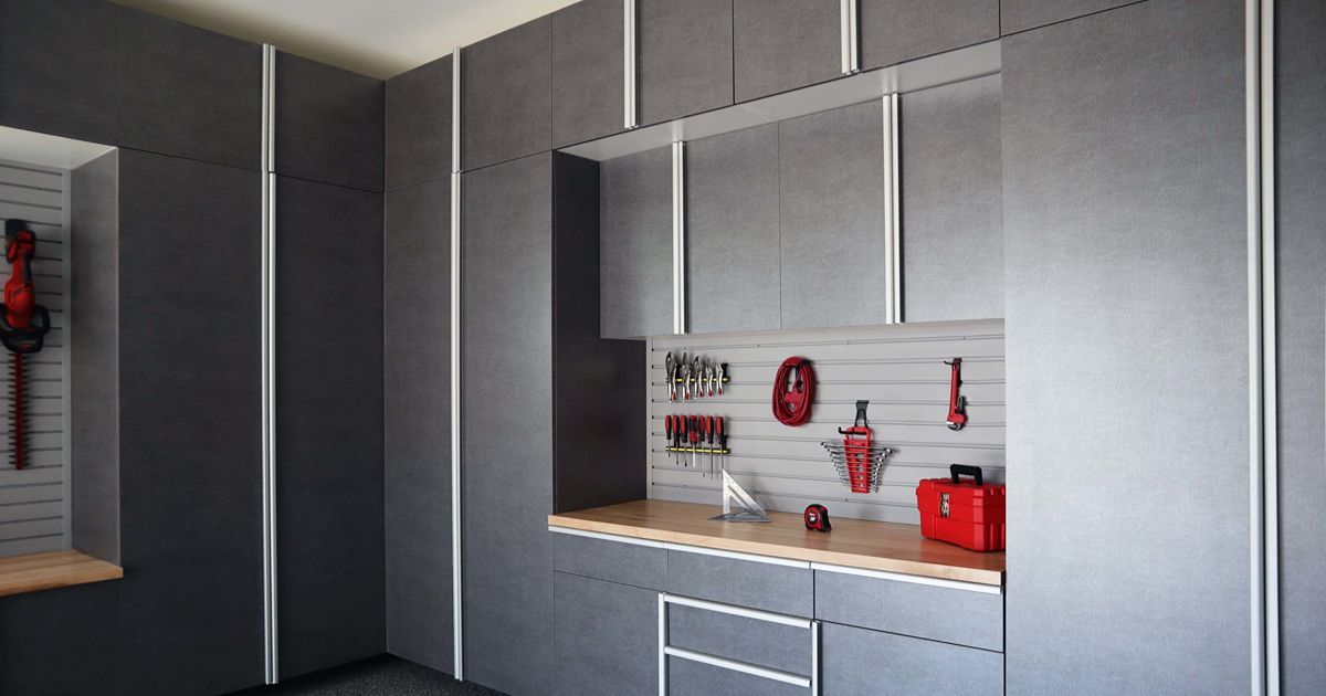 Dark gray garage cabinets with tools hanging on a pegboard, with a wooden countertop.