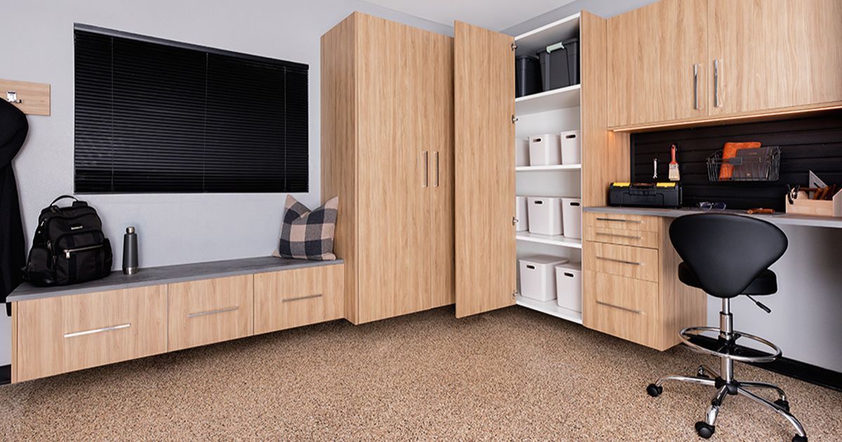 Modern garage with light wood cabinets, desk, bench, and black accents.