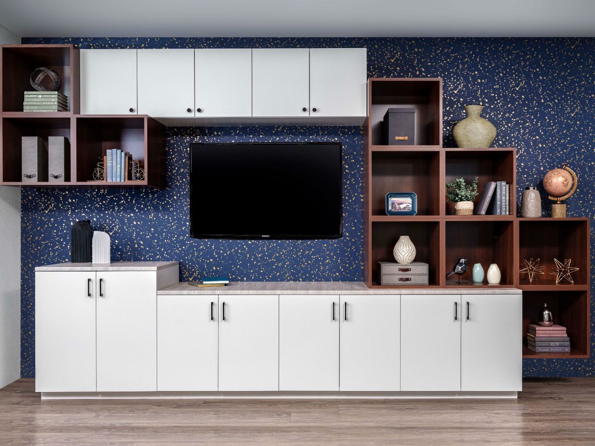 White and brown cabinetry with a TV against a blue speckled wall.