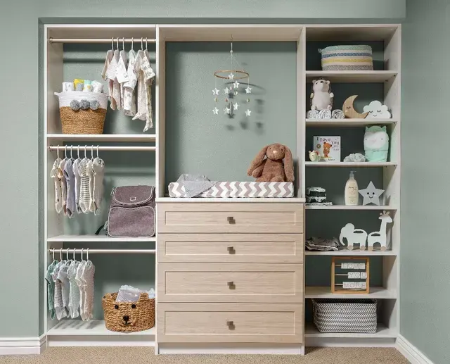 Baby nursery closet with hanging clothes, shelves, and a changing station.