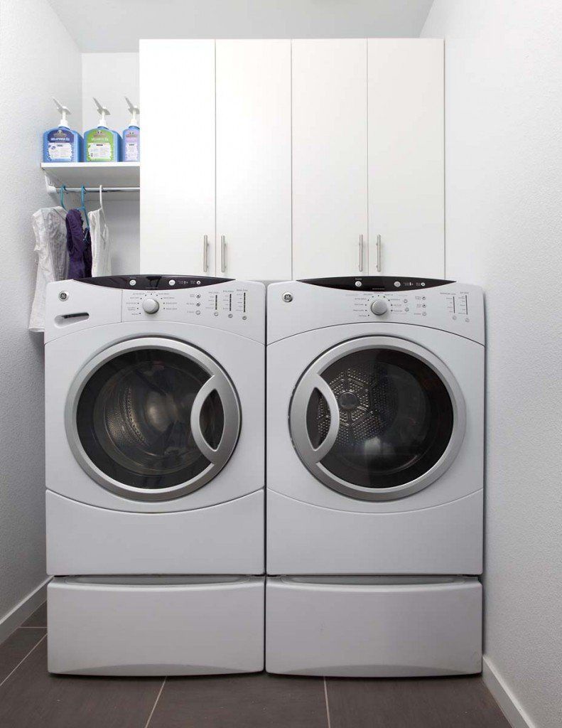A laundry room with two white washers and dryers