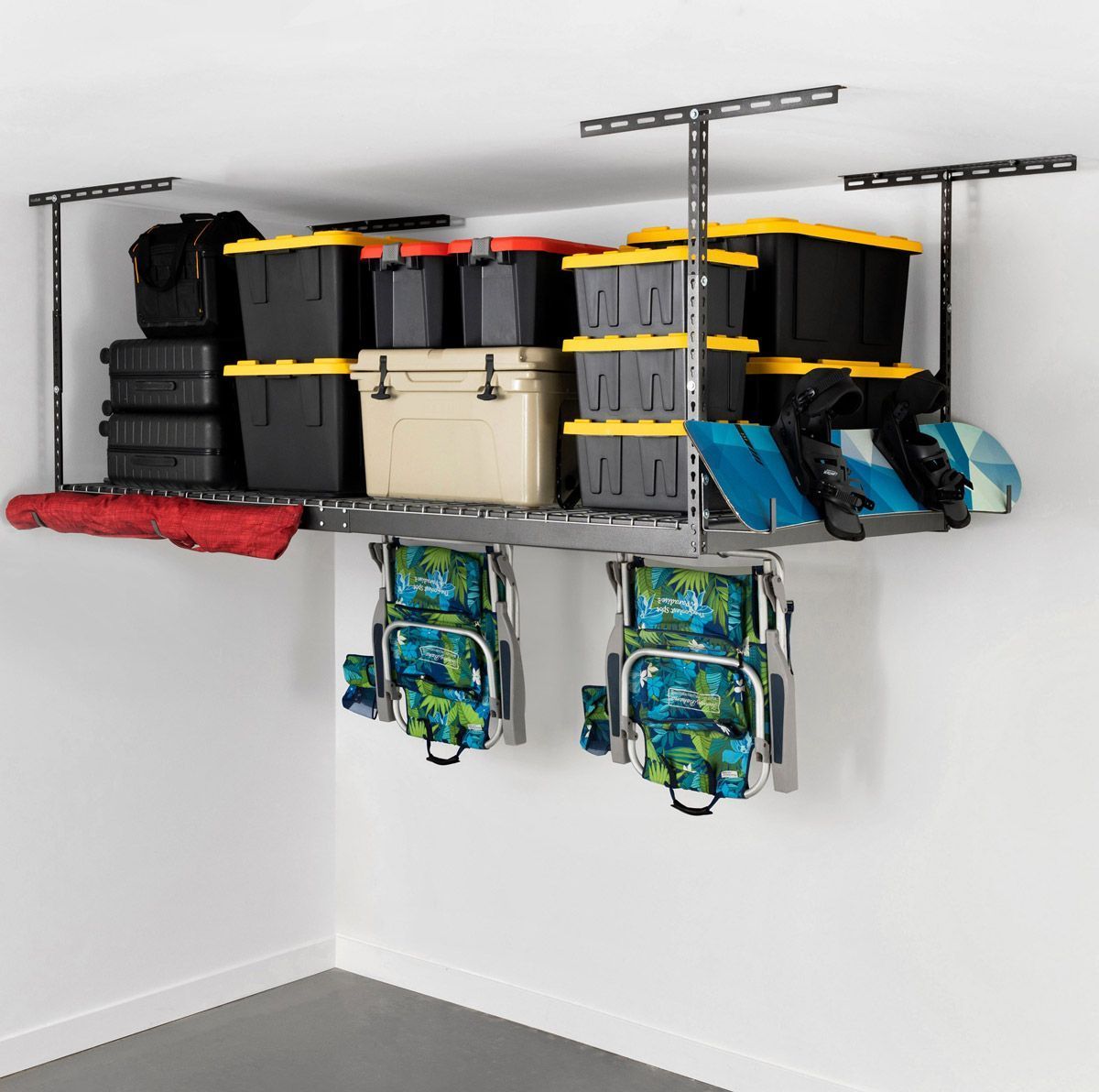 Overhead garage storage system with containers, chairs, and gear against a white wall.