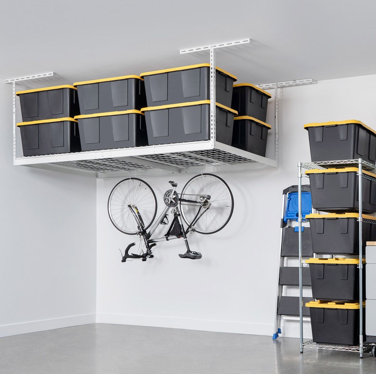 White garage with ceiling storage, bicycle, and stacked storage bins in black and yellow.