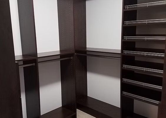 Dark brown closet organizer with shelves and hanging rods; white walls.