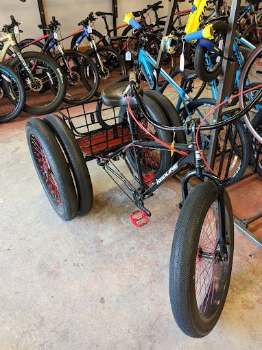 A three wheeled bicycle is parked in a row of bicycles.