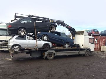 three scrap cars getting towed
