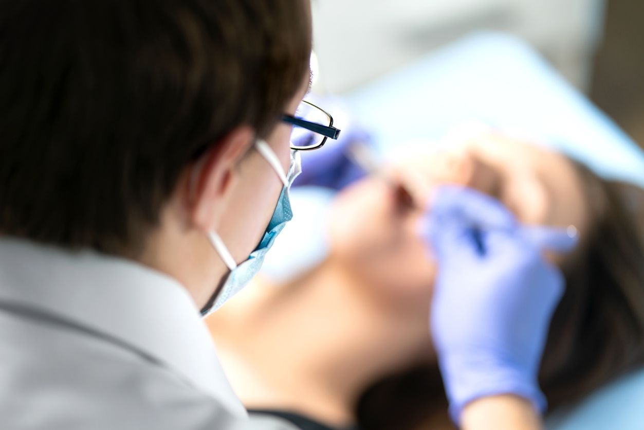 Dentist examining a patient’s mouth with gloved hands in a clinic