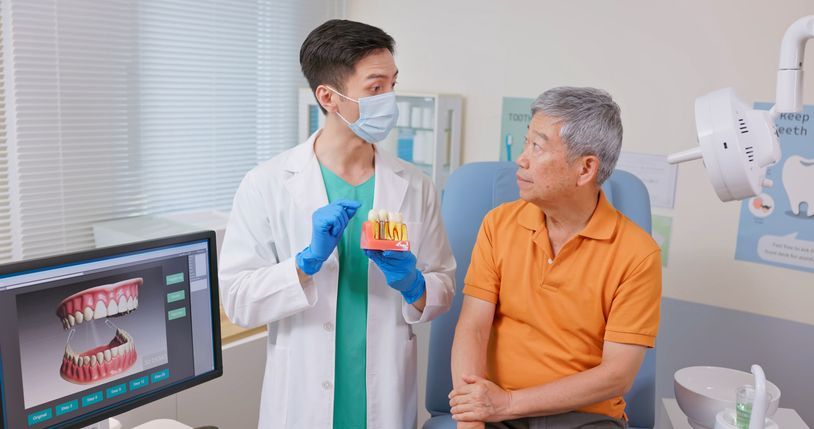 Dentist examining patient's teeth with shade guide in clinic. Two medical professionals, one patient.