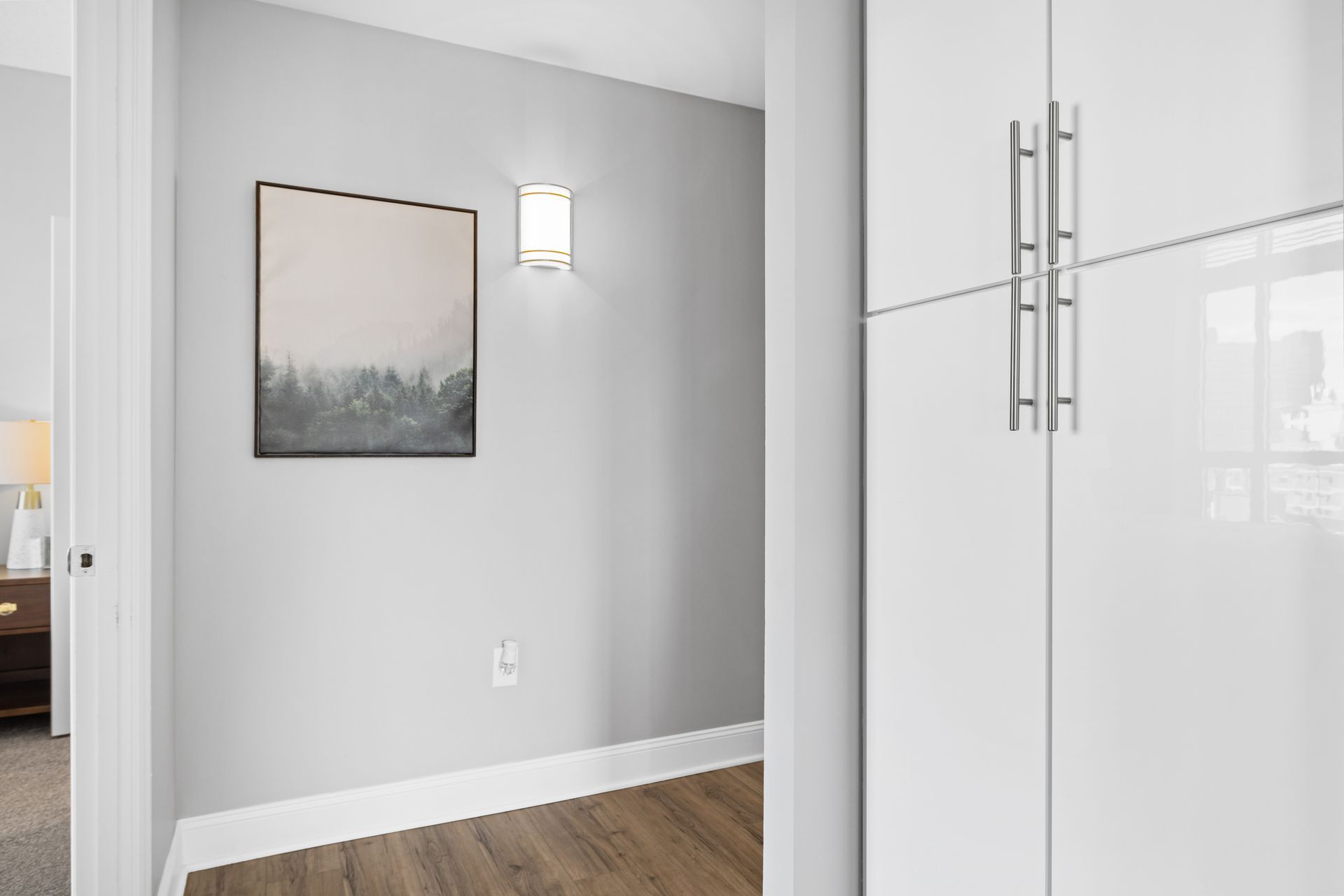 A hallway with a painting on the wall and a white cabinet.