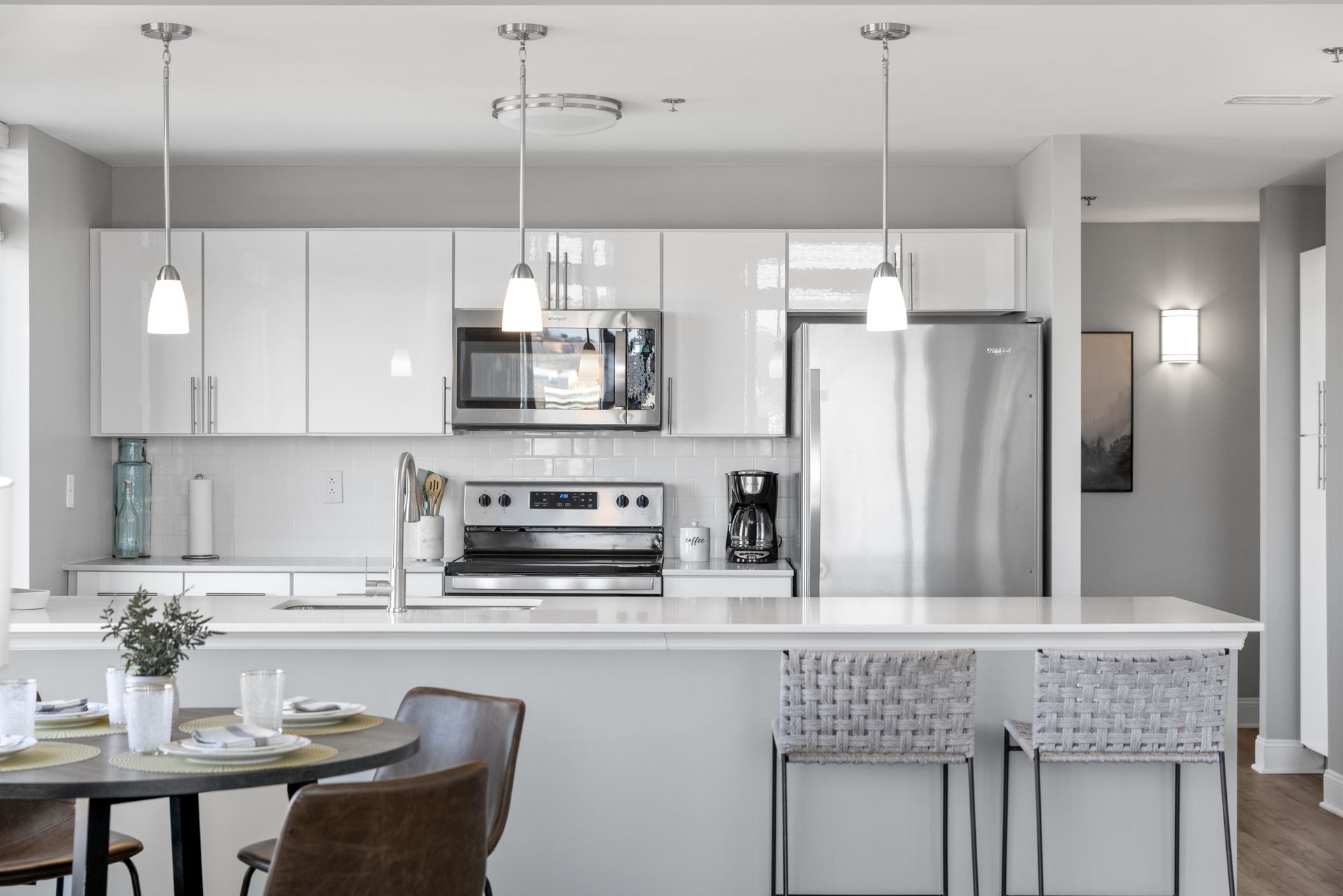 A kitchen with white cabinets , stainless steel appliances , a table and chairs.